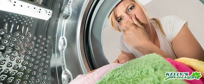 KDC Close-up Of Young Woman Inserting Stinky Clothes In Washing Machine